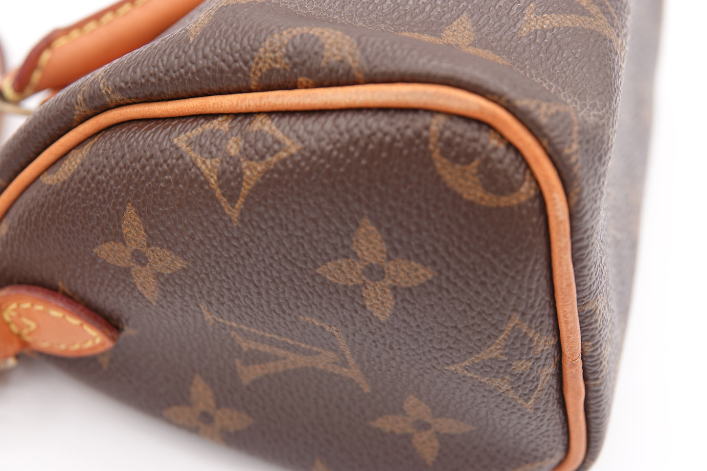 Close-up of a brown leather handbag with a prominent logo pattern on a white background