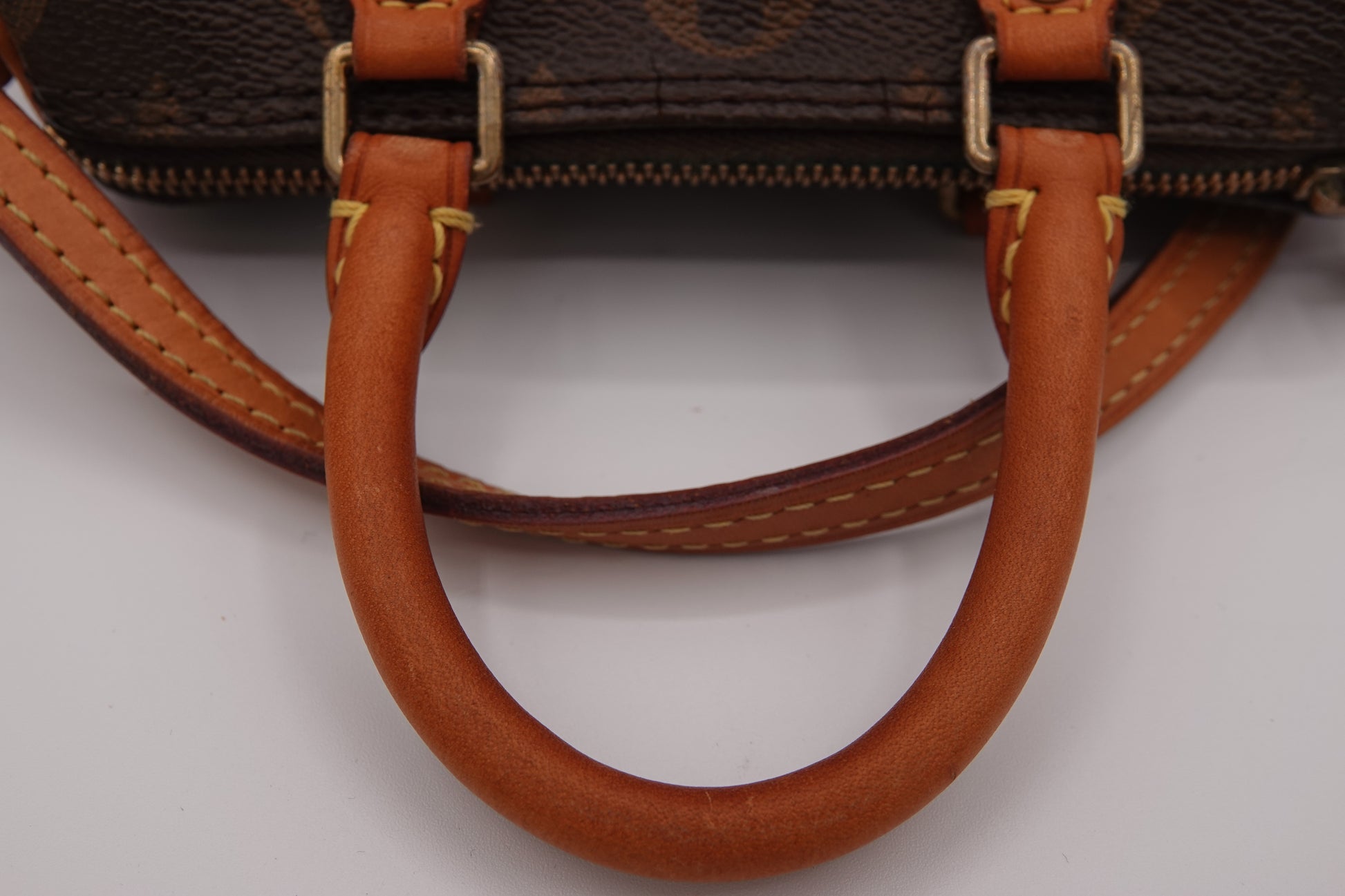 Close-up of a brown handbag with leather handles on a white background