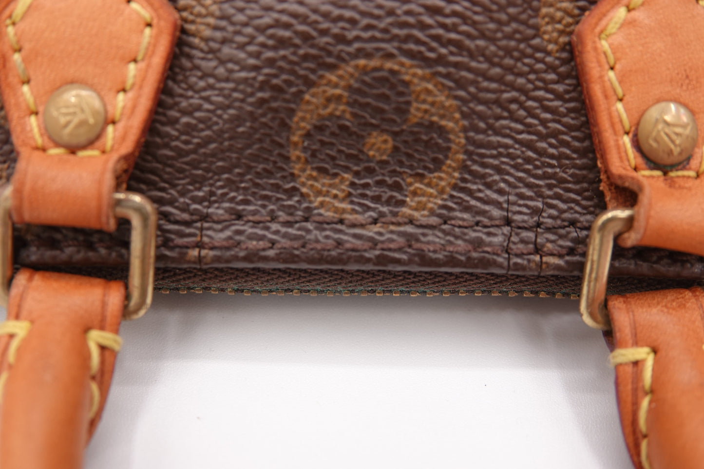 Close-up of a brown leather handbag with gold hardware on a white background