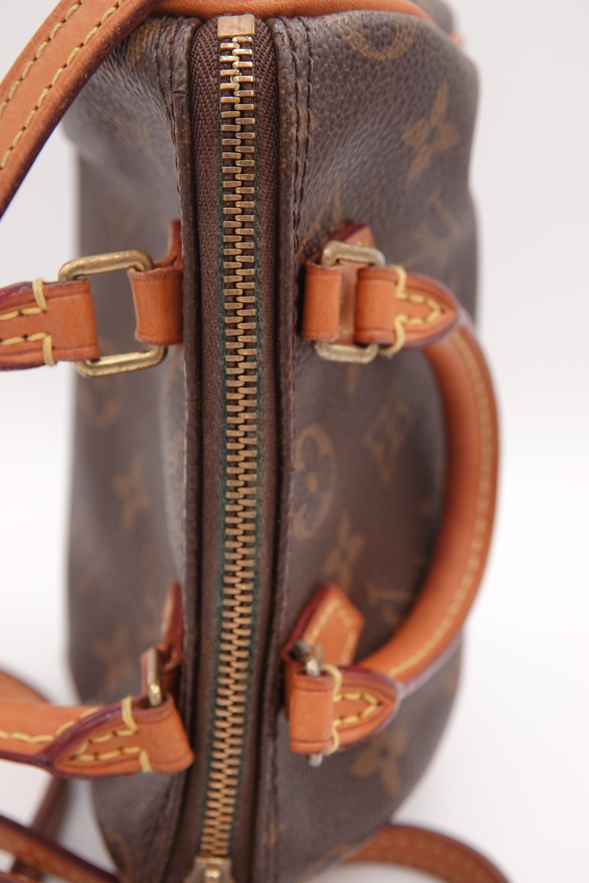 Brown handbag with gold zipper and hardware on a white background