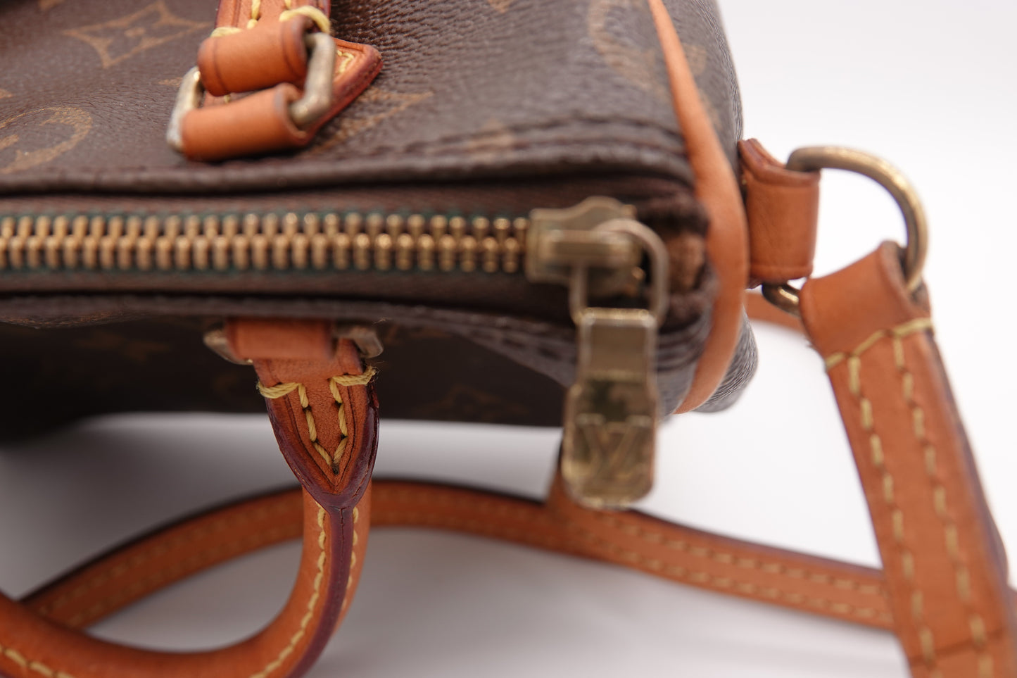 Close-up of a brown leather handbag with gold zipper and hardware.