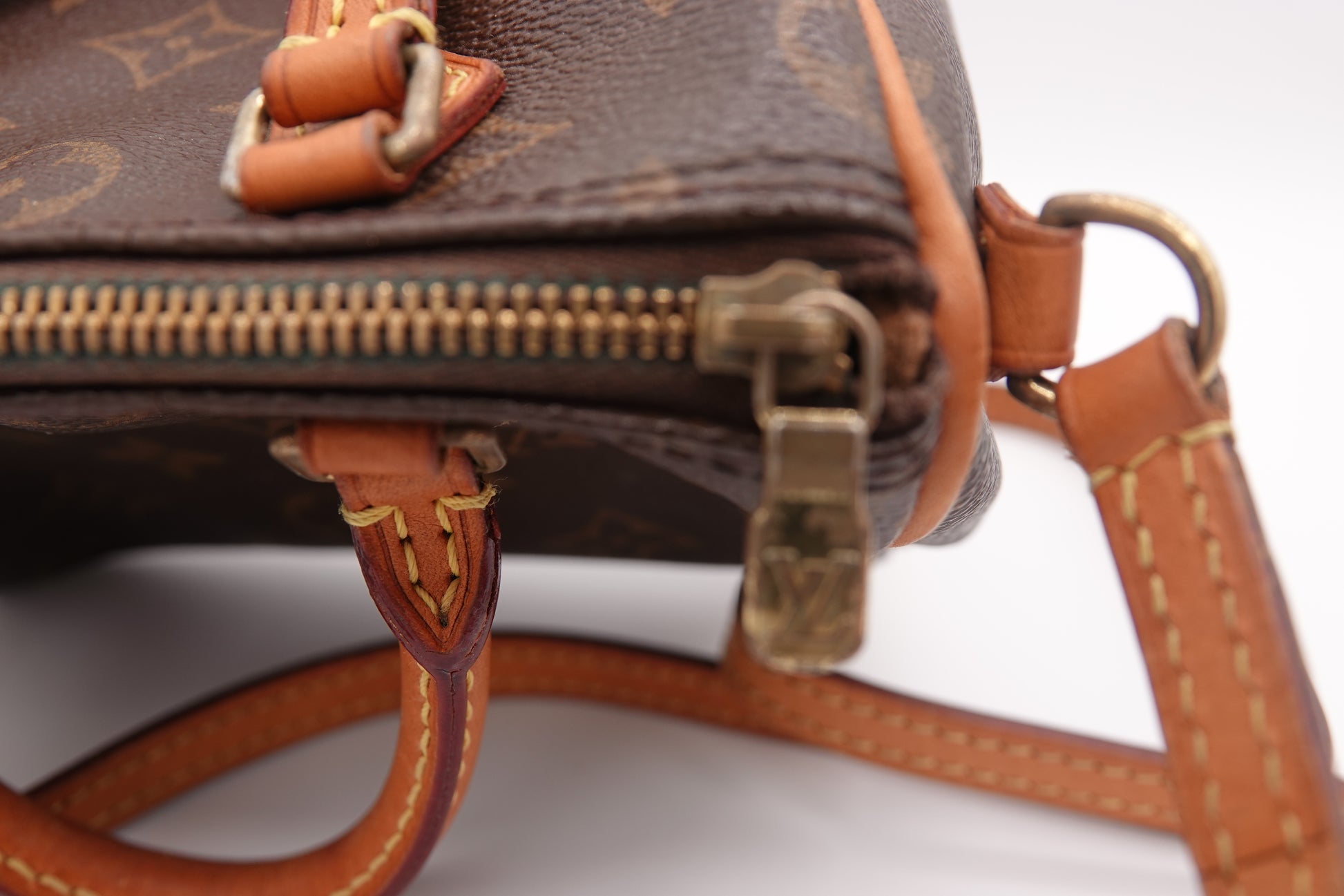 Close-up of a brown leather handbag with gold zipper and hardware.