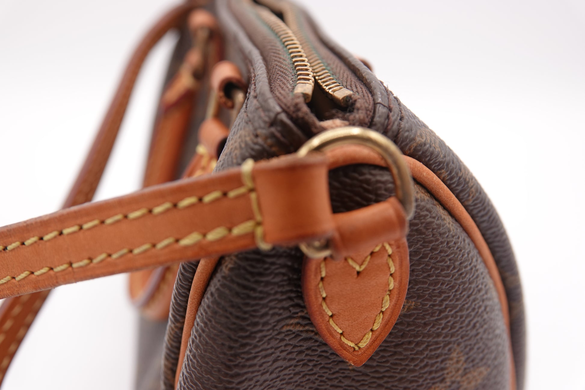 Close-up of a brown leather handbag with heart-shaped detail on a white background