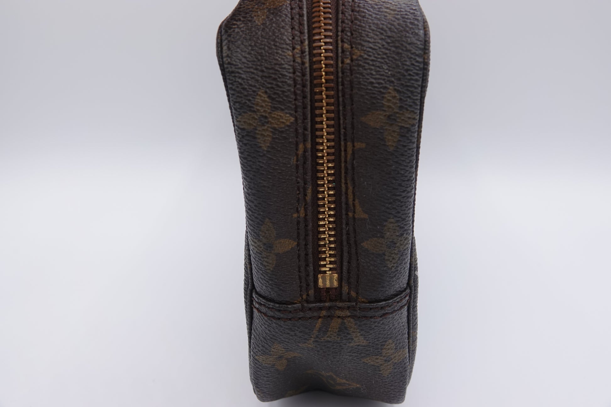 Louis Vuitton monogram toiletry bag with gold zipper on a white background