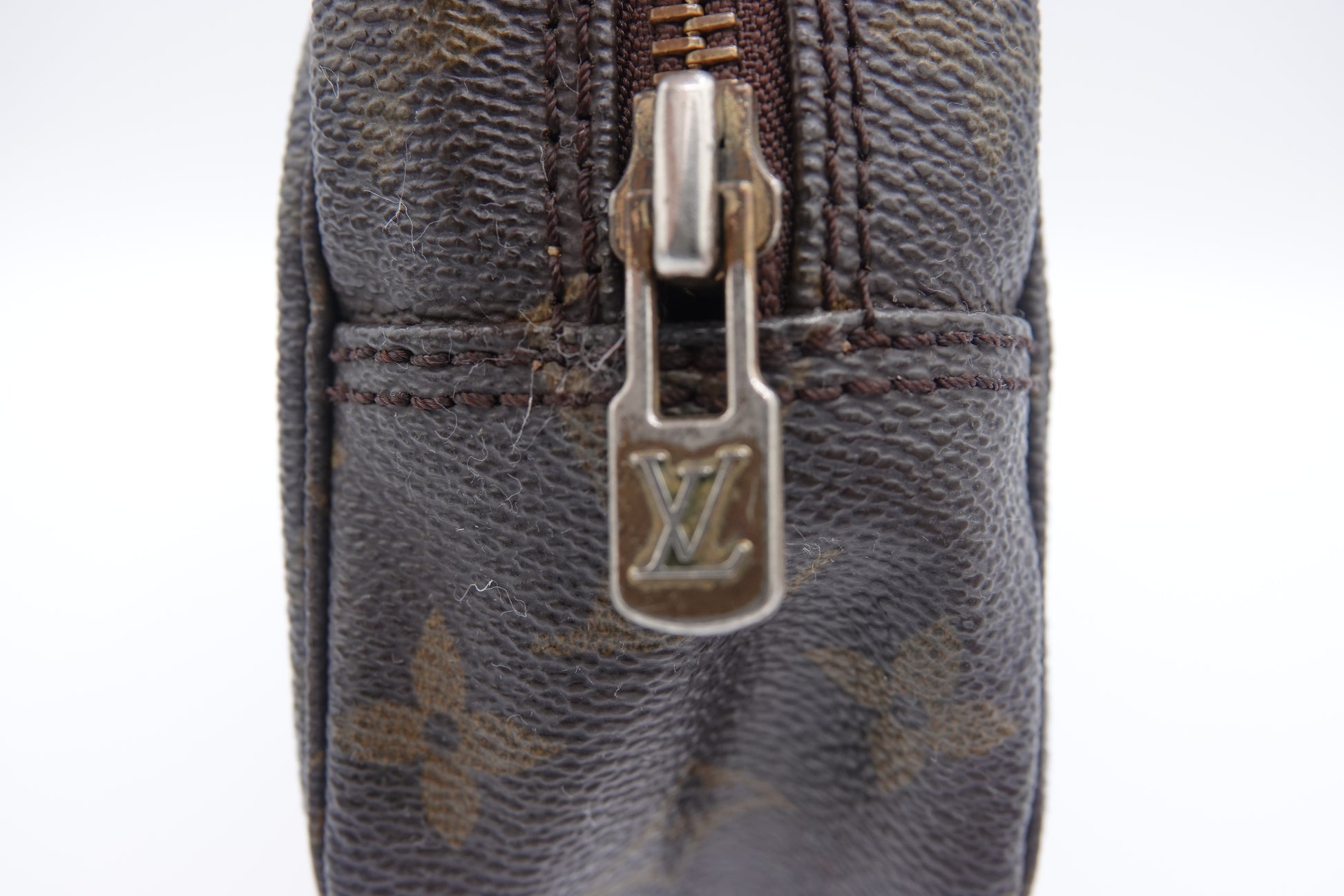 Close-up of a Louis Vuitton monogram bag with a zipper on a white background