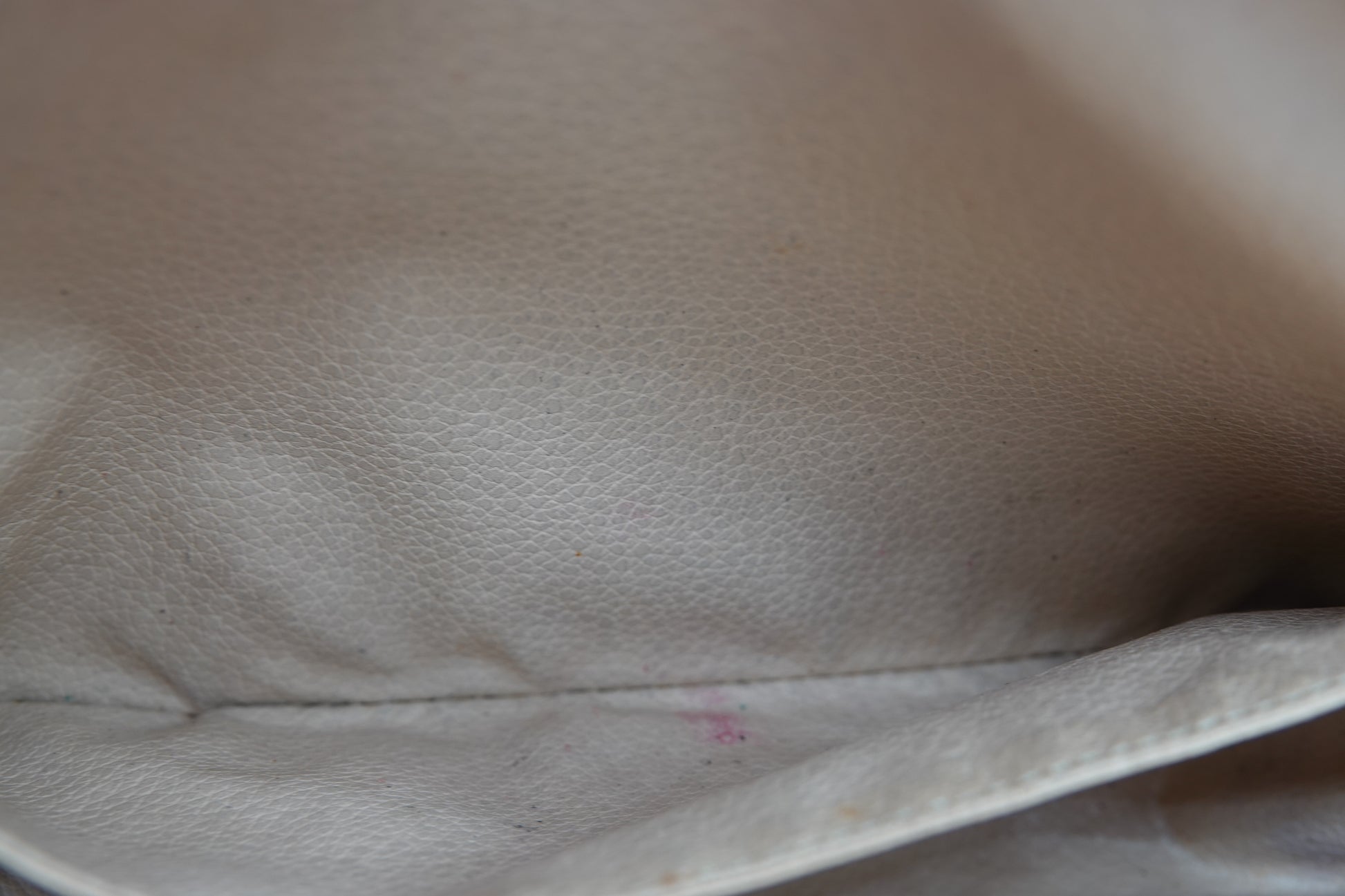 Close-up of beige fabric with a visible seam and slight discoloration.