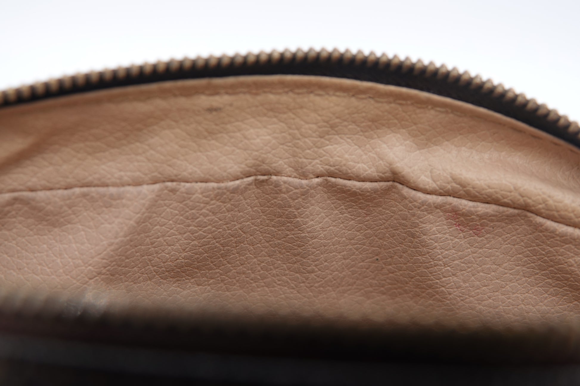 Close-up of a brown leather bag with a zipper on a white background