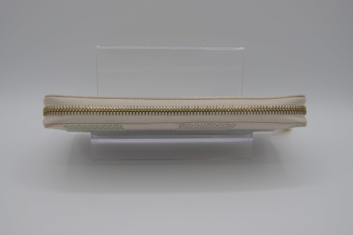 Beige zipper on a clear stand against a white background