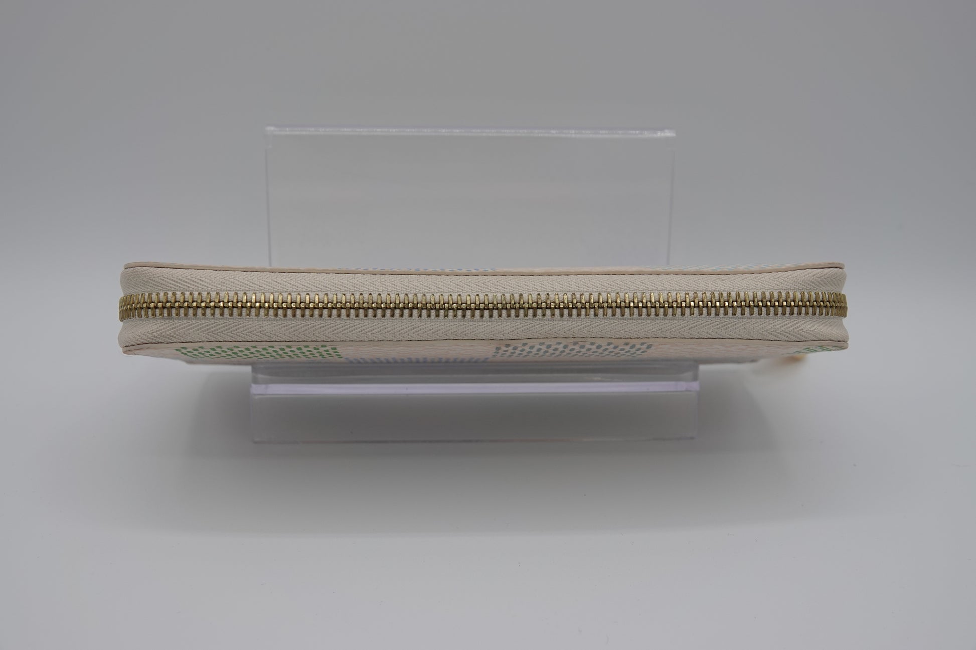 Beige zipper on a clear stand against a white background