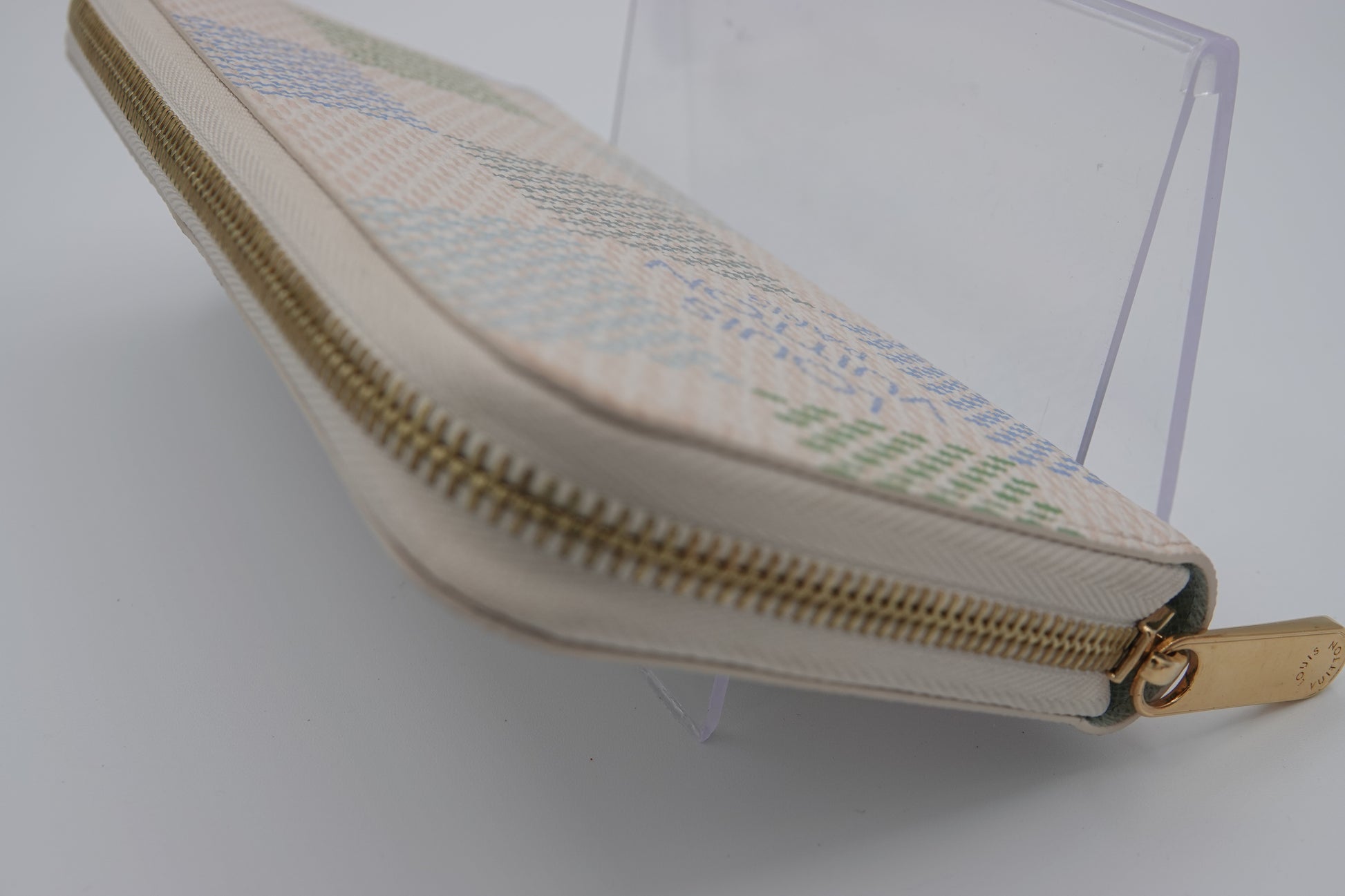 Fabric pouch with a zipper on a clear stand against a white background