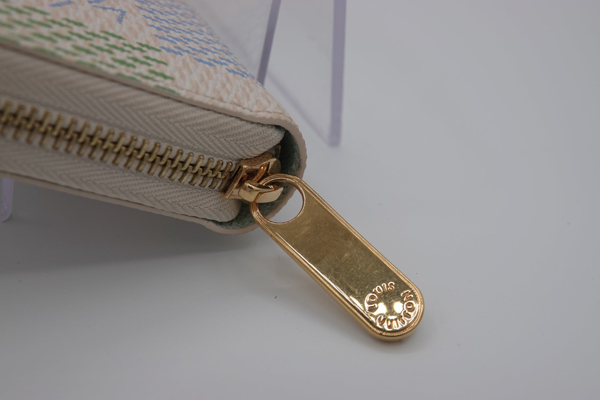 Close-up of a beige wallet with a gold zipper on a light gray background