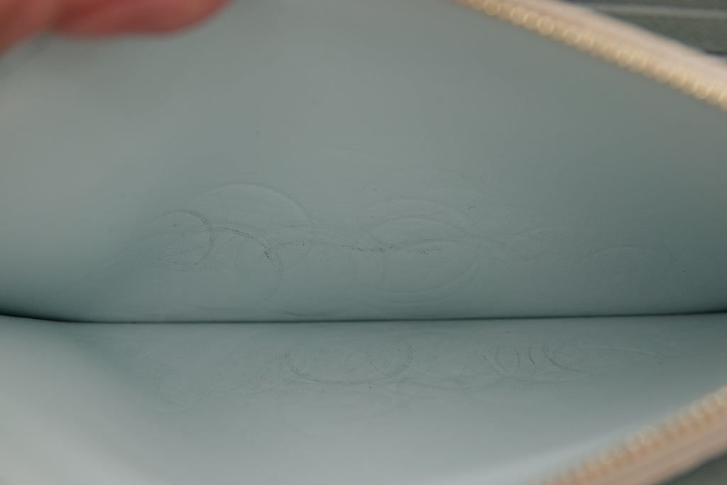 Close-up of a light blue leather pouch with an embossed design.