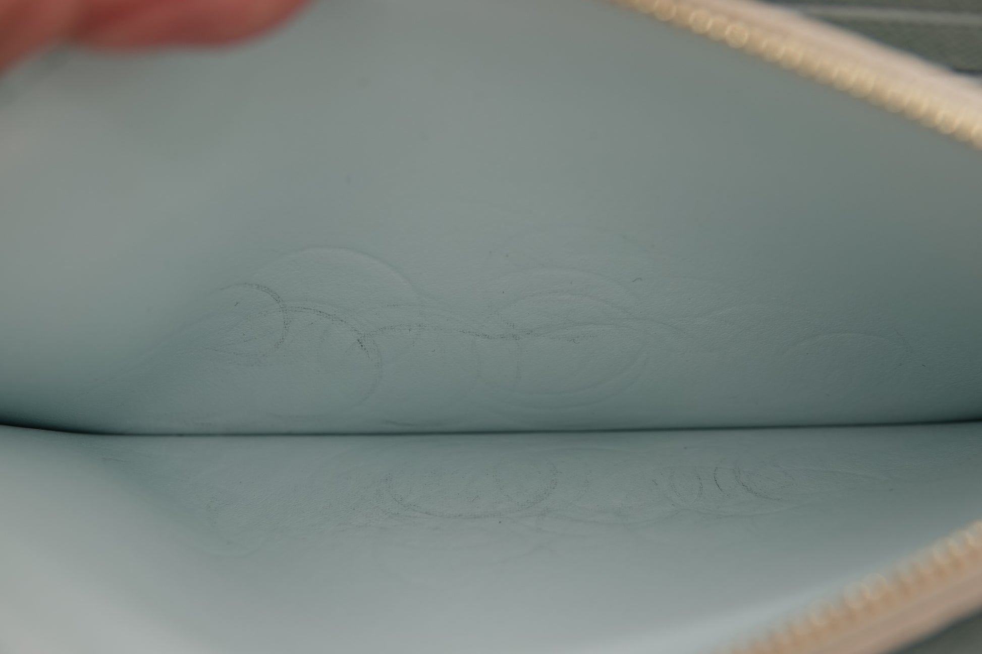 Close-up of a light blue leather pouch with an embossed design.