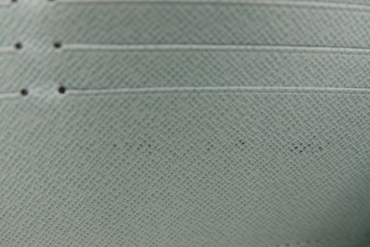 Close-up of a textured light green fabric with visible stitching