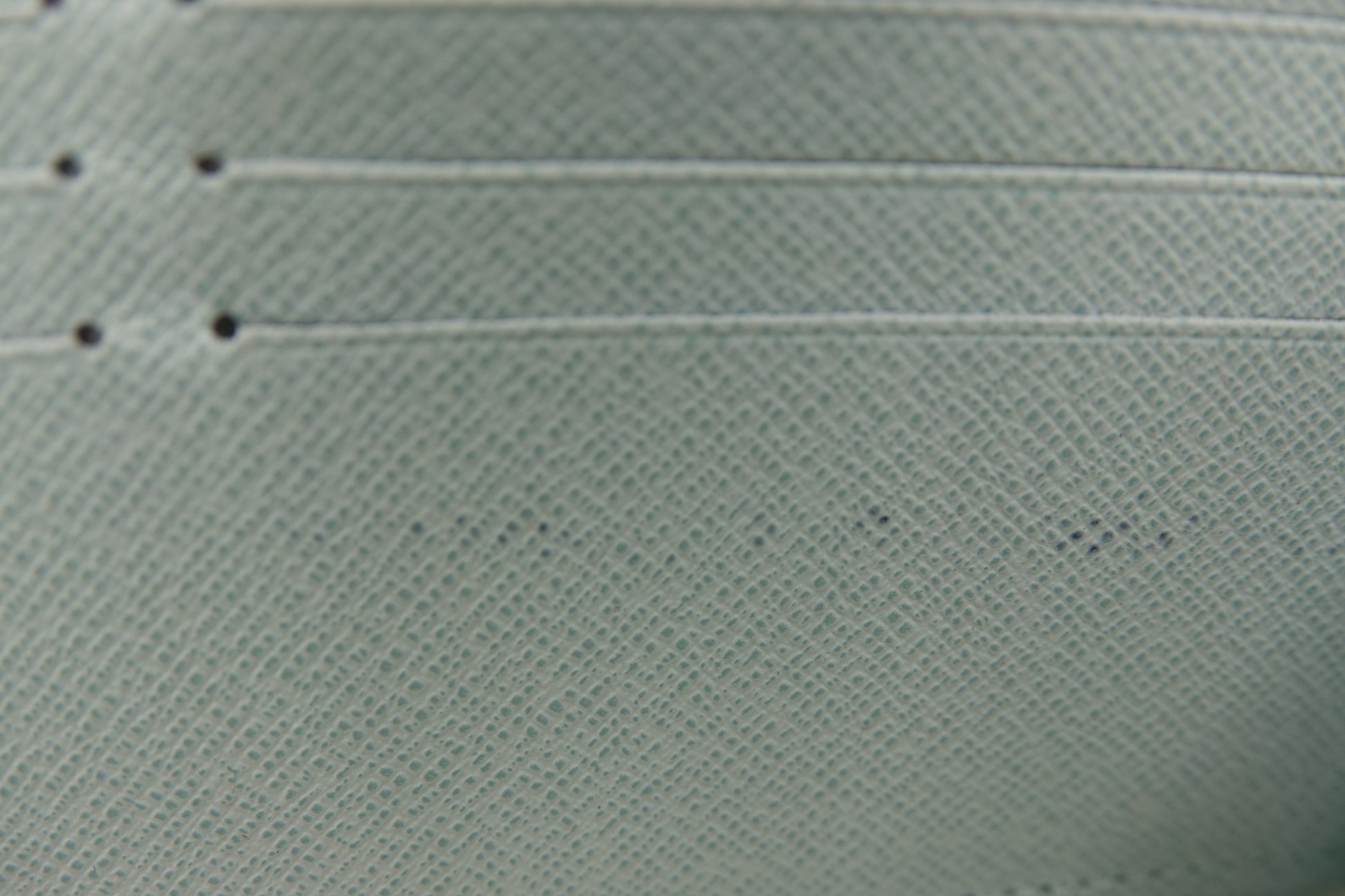 Close-up of a textured light green fabric with visible stitching