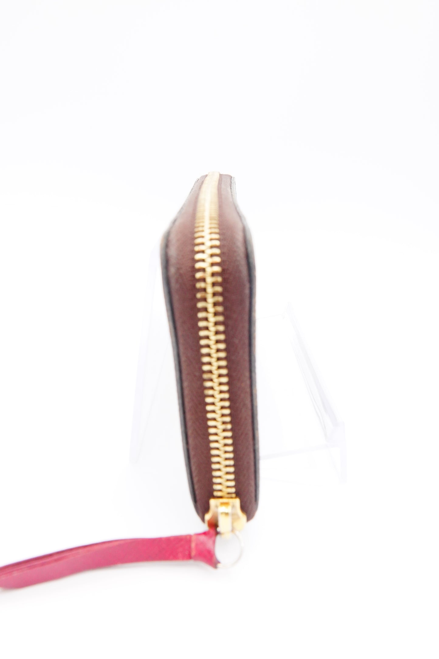 Brown pouch with gold zipper and pink strap on a white background