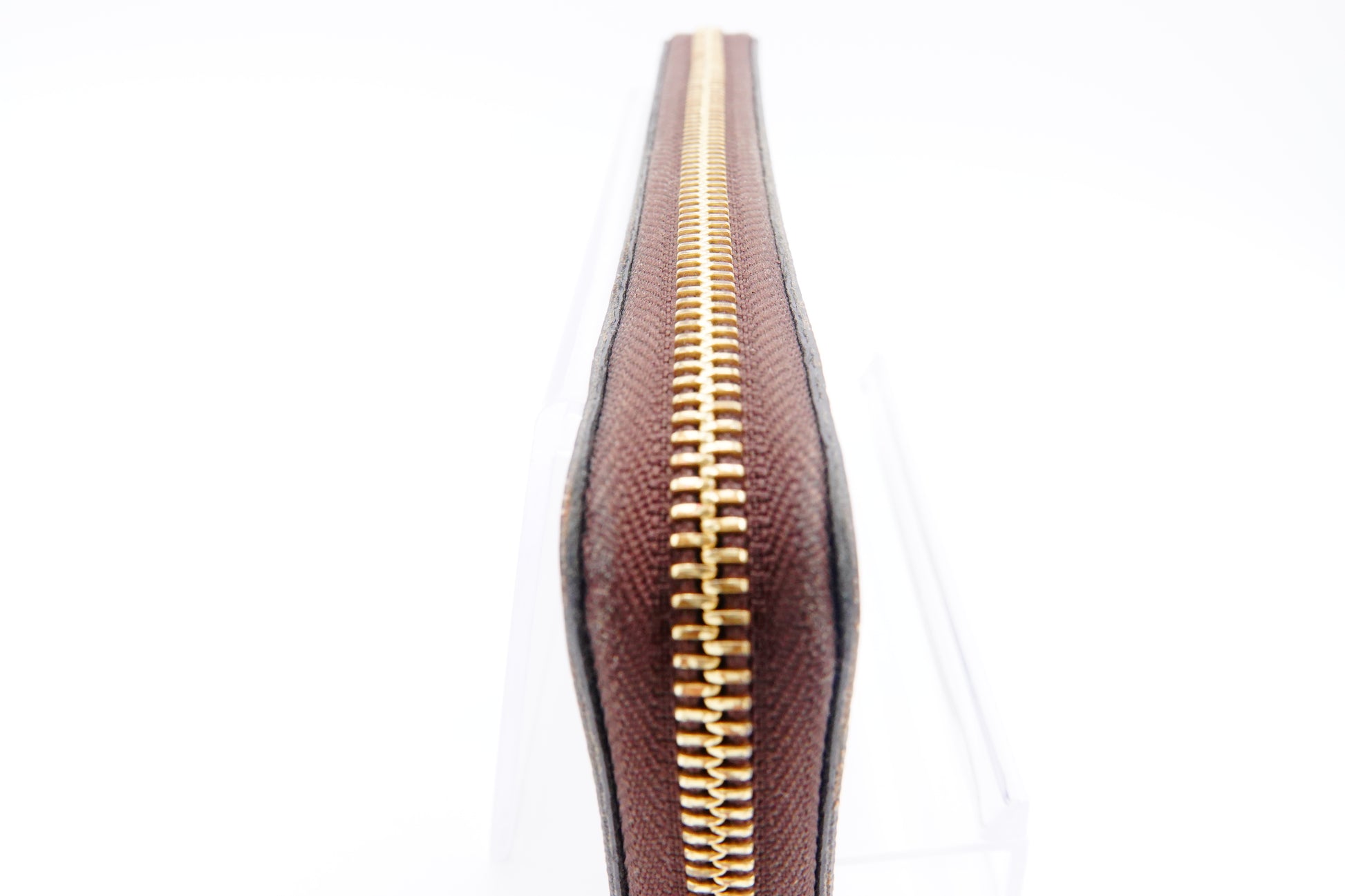 Close-up of a brown leather wallet with a gold zipper on a white background