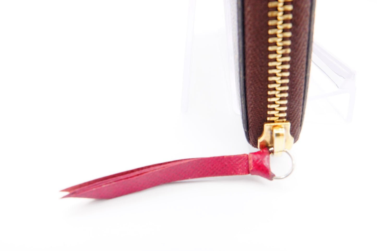 Close-up of a brown wallet with a gold zipper and pink tassel on a white background