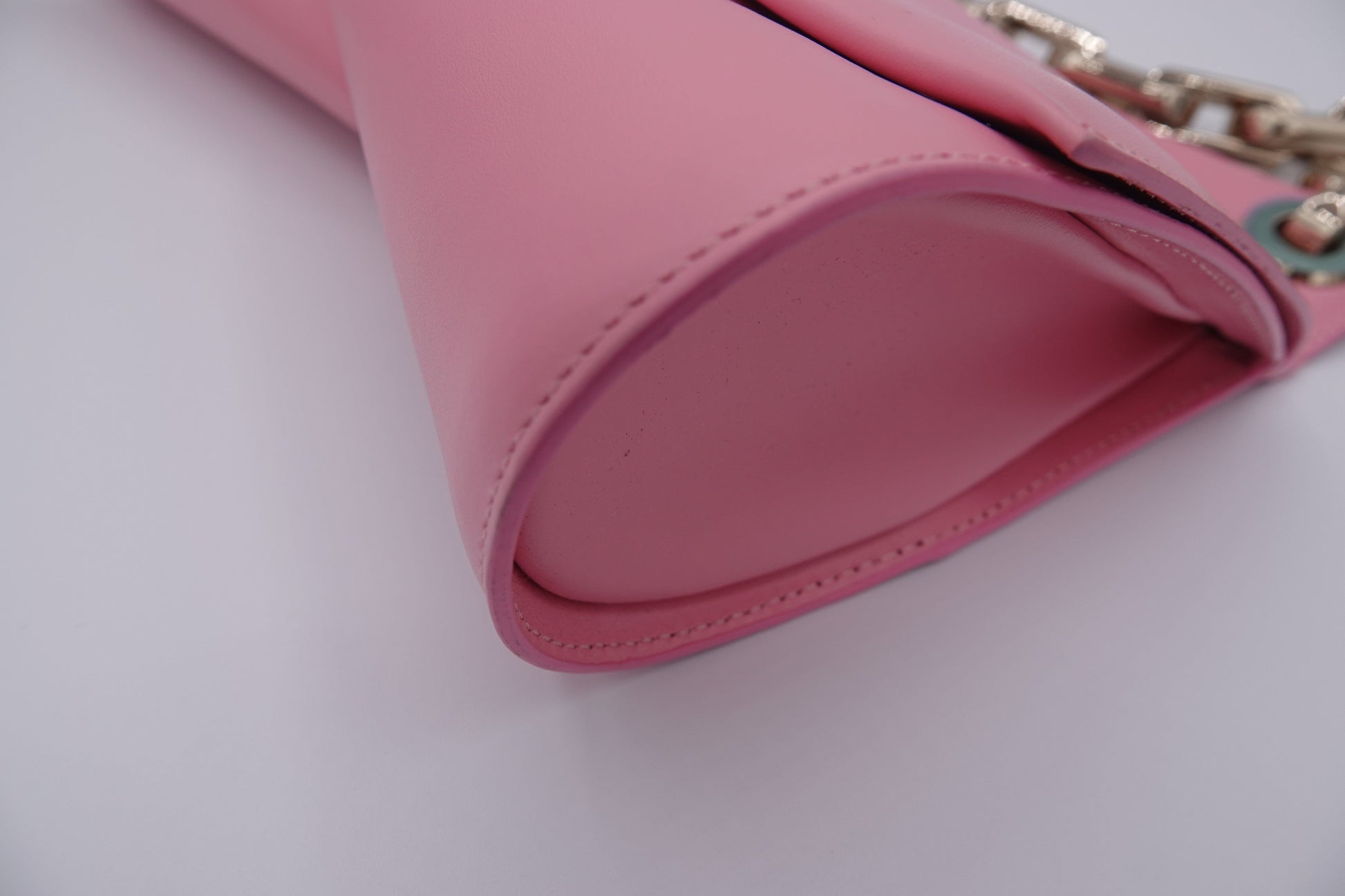 Close-up of a pink handbag with a chain detail on a white background