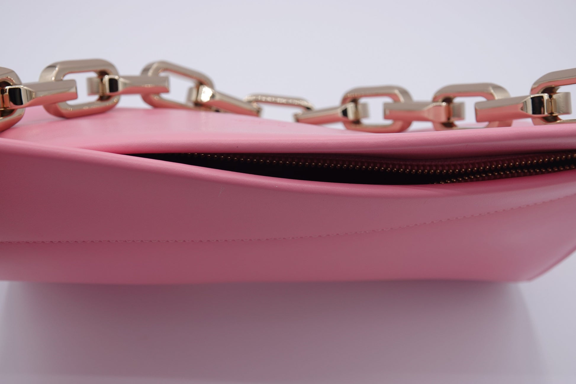Pink handbag with gold chain detail on a white background
