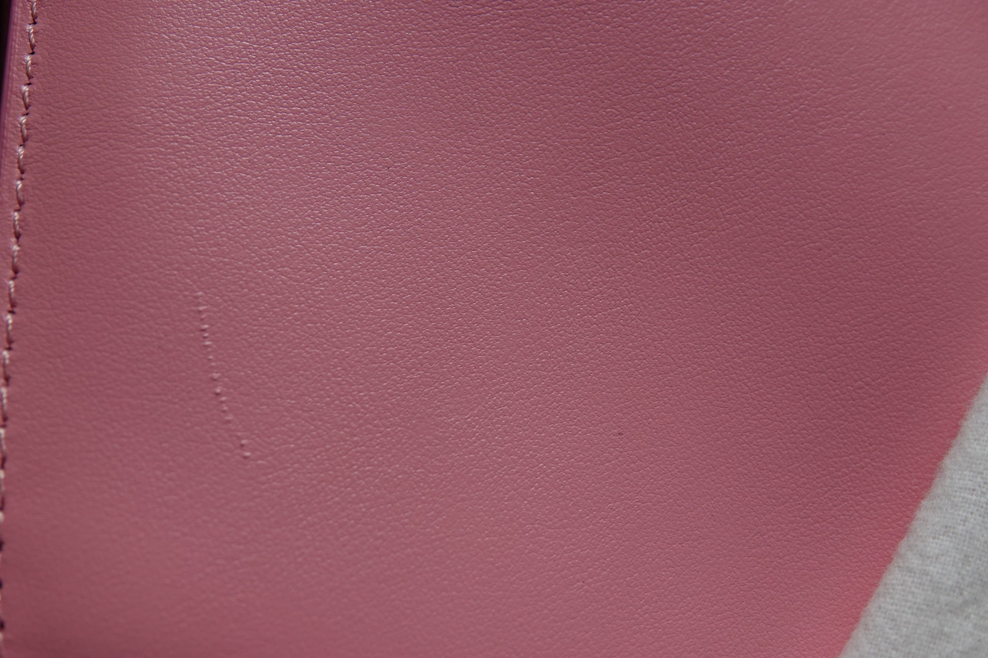 Close-up of a maroon leather surface with visible stitching