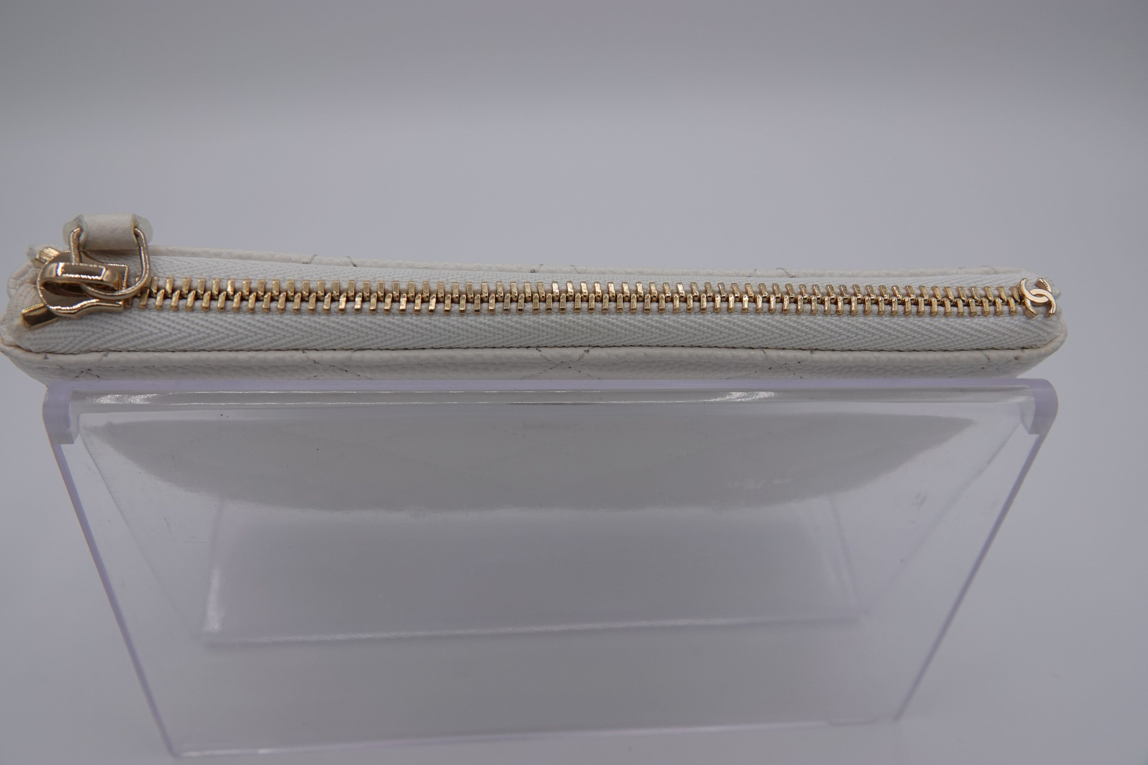 Clear pouch with gold zipper on a light gray background