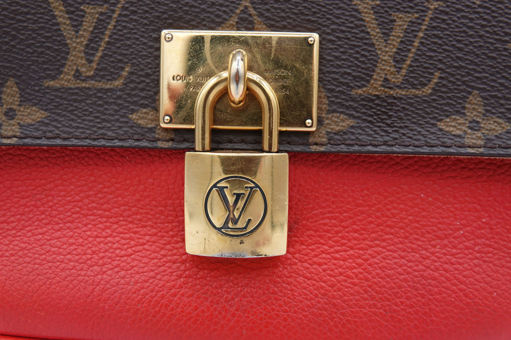 Gold padlock with Louis Vuitton logo on a red and monogrammed background