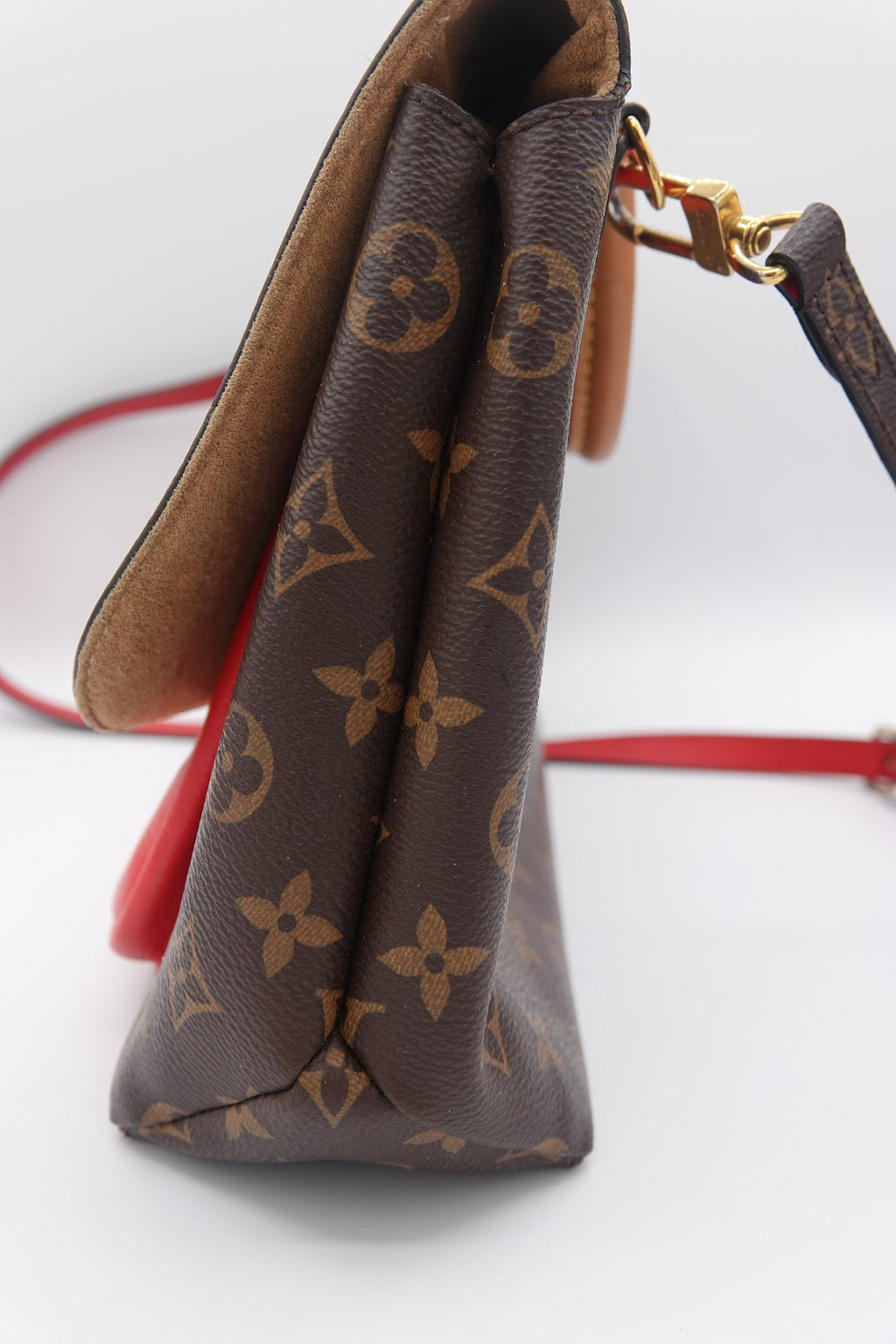 Close-up of a brown leather pouch with gold monogram pattern on a white background