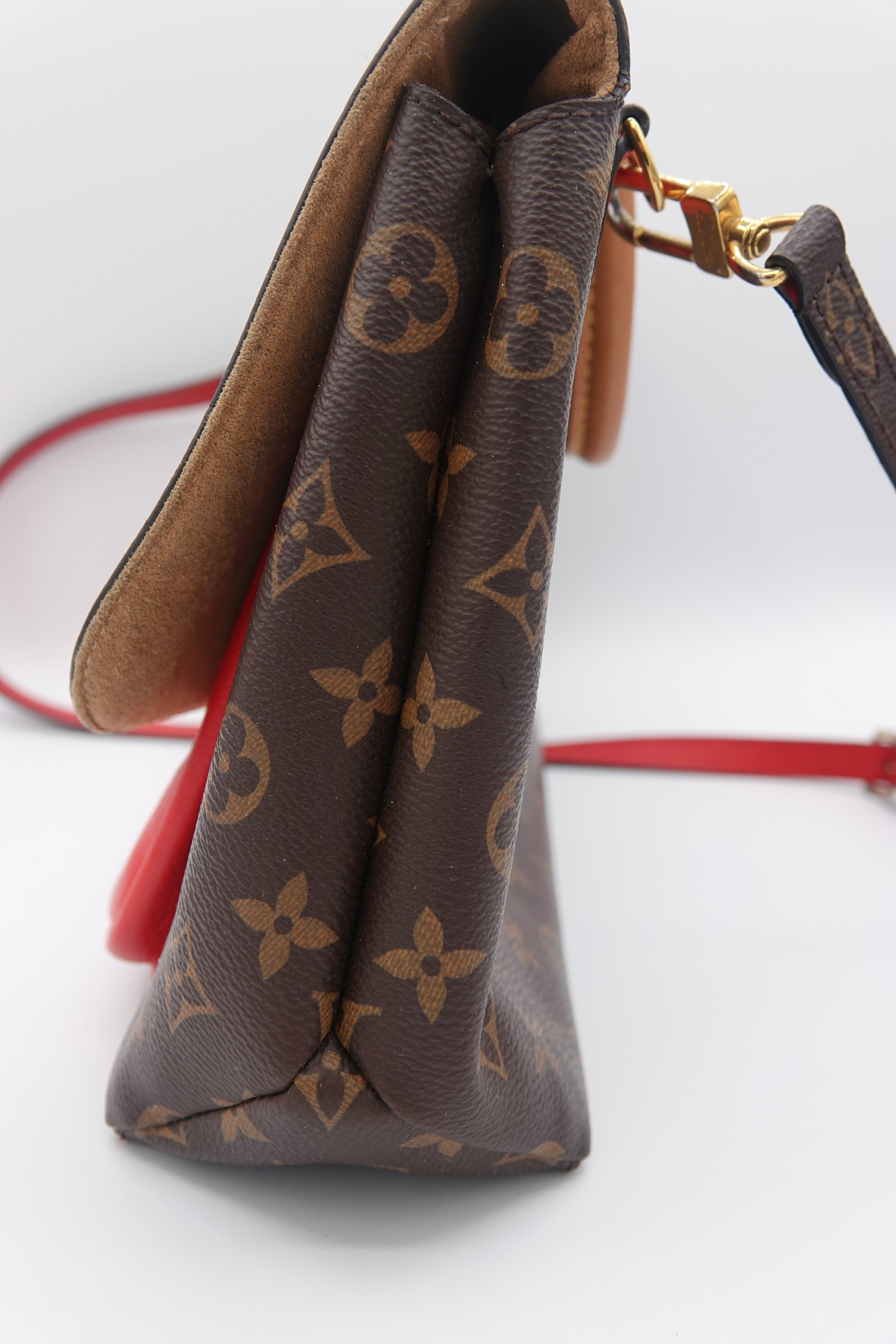 Close-up of a brown patterned handbag with gold hardware on a white background