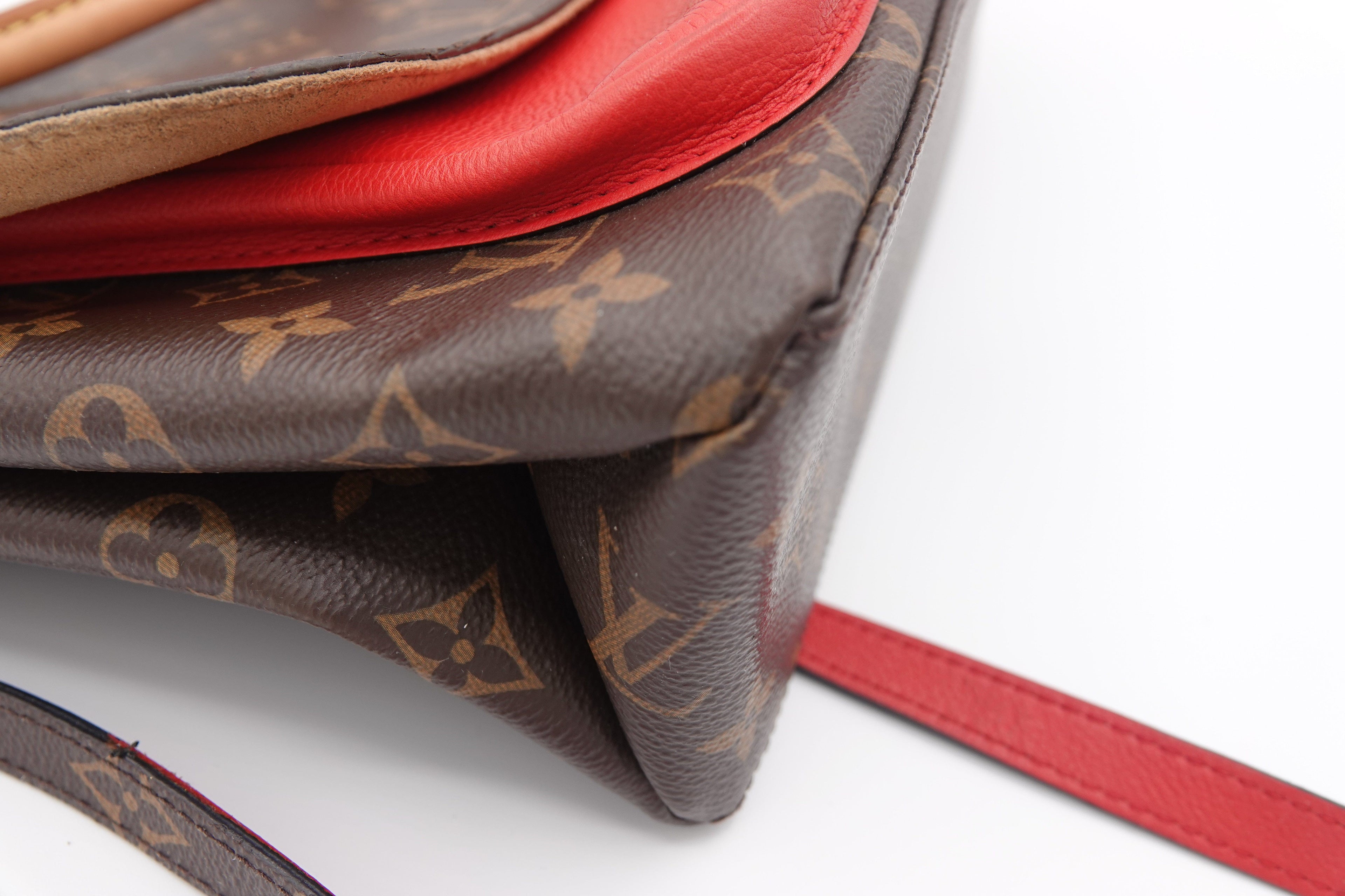 Designer handbag with red interior and monogram pattern on a white background