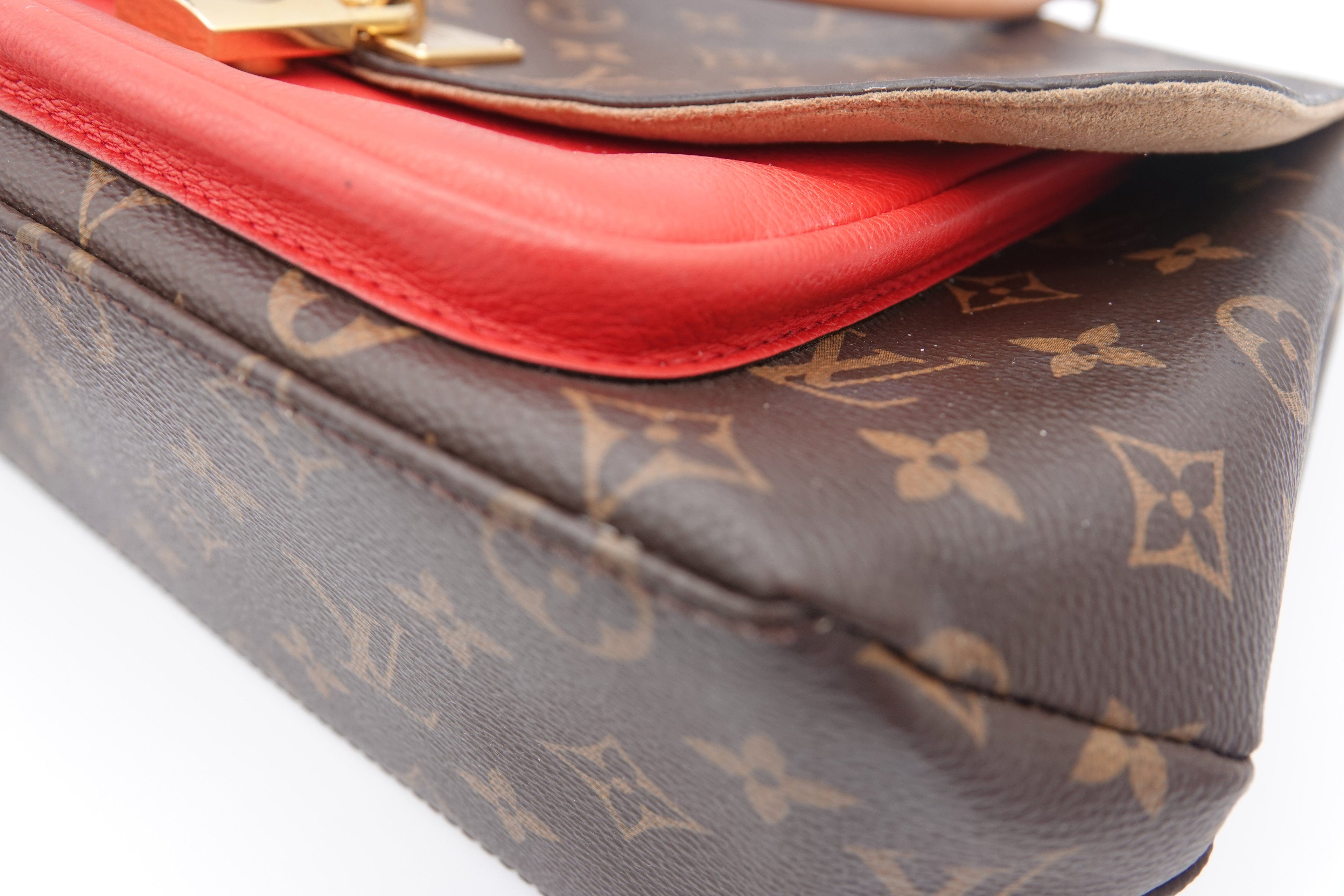 Designer handbag with red interior lining and monogram pattern on surface
