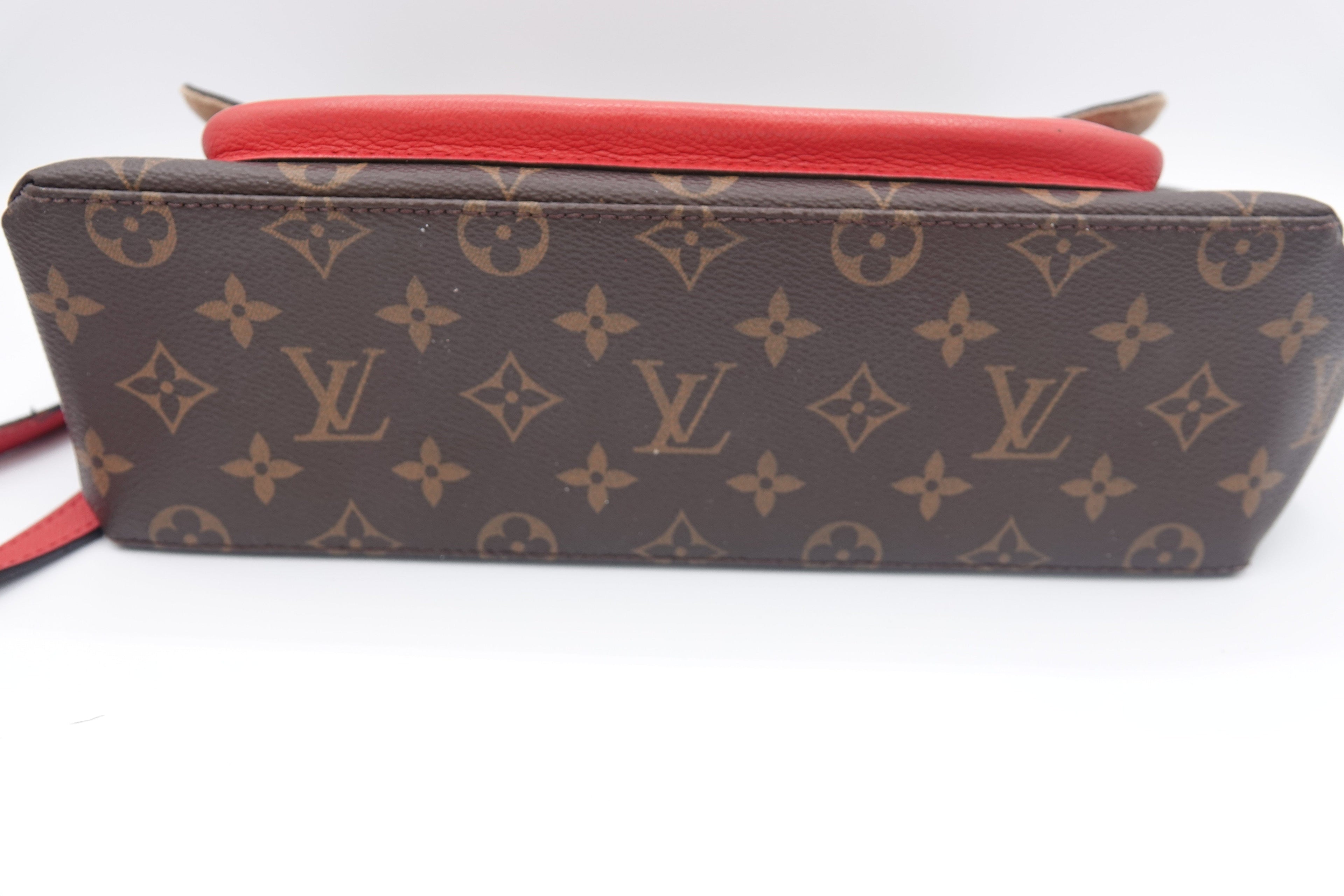 Louis Vuitton monogram handbag with red interior on a white background