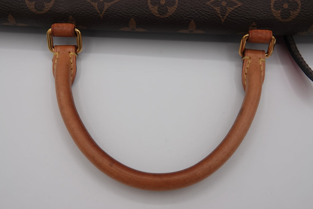 Close-up of a brown leather handle with gold hardware on a Louis Vuitton bag.