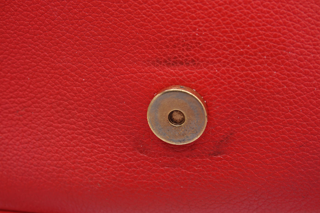 Close-up of a red leather surface with a gold button