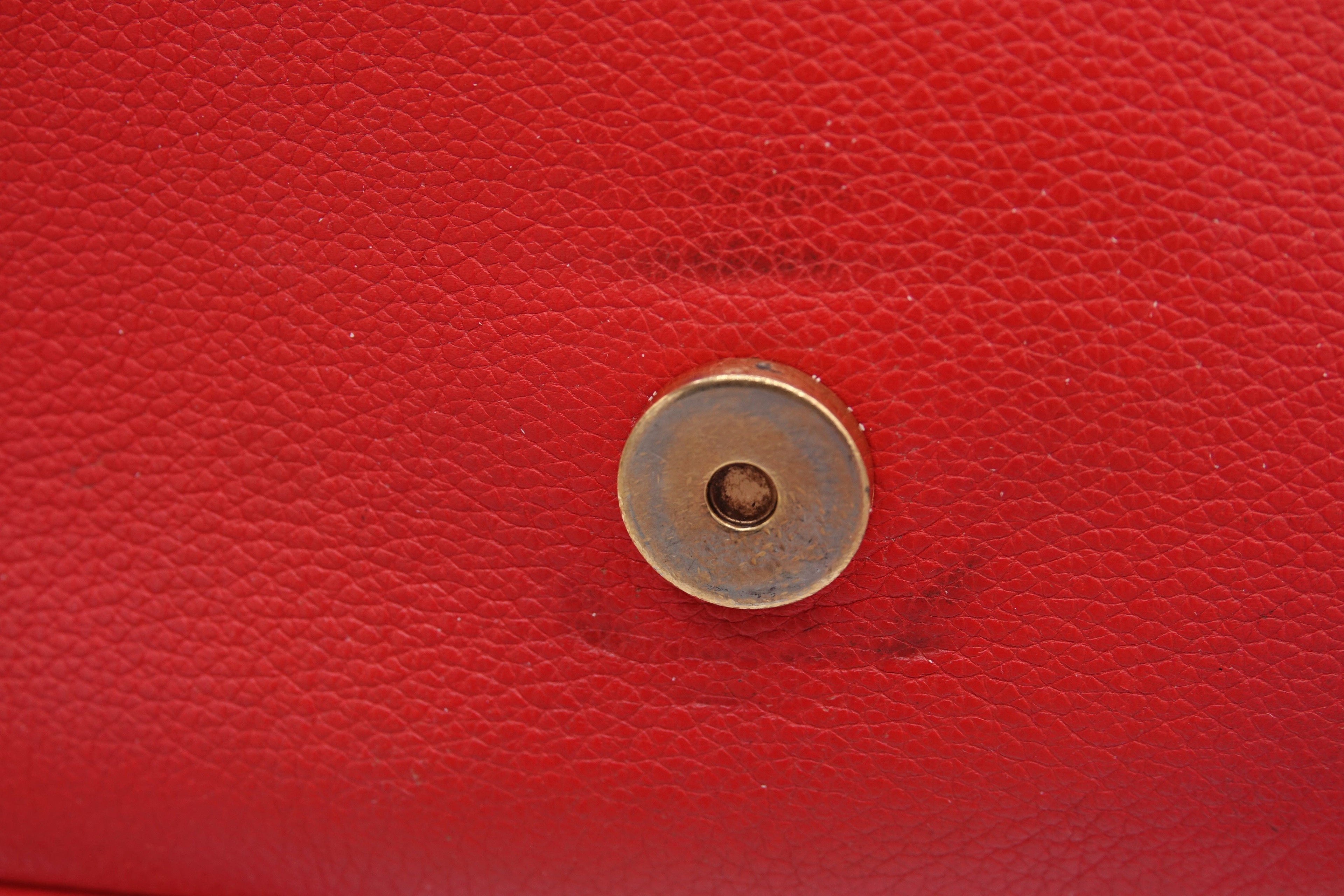 Close-up of a red leather surface with a gold button