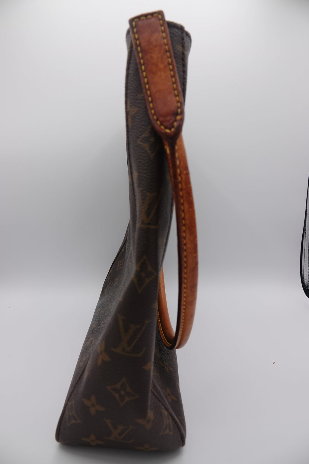 Brown leather handbag with monogram pattern on a white background