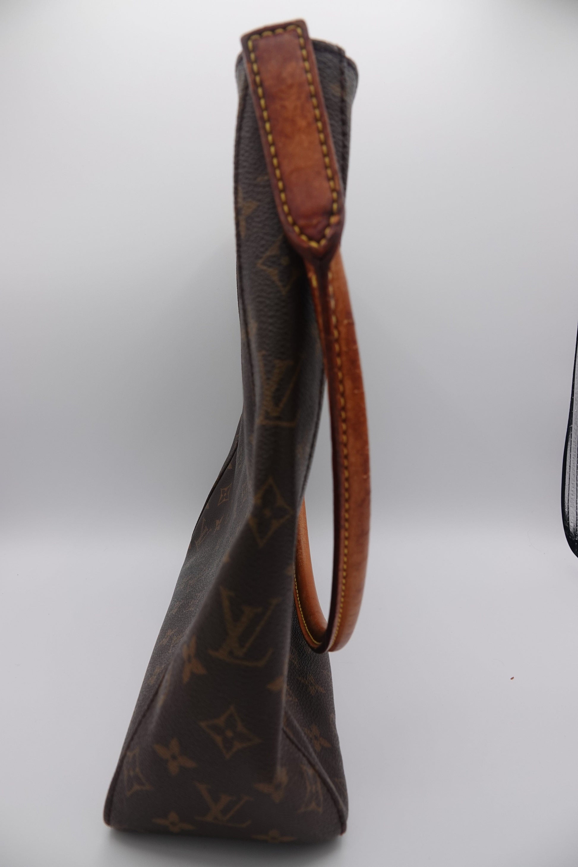 Brown leather handbag with monogram pattern on a white background