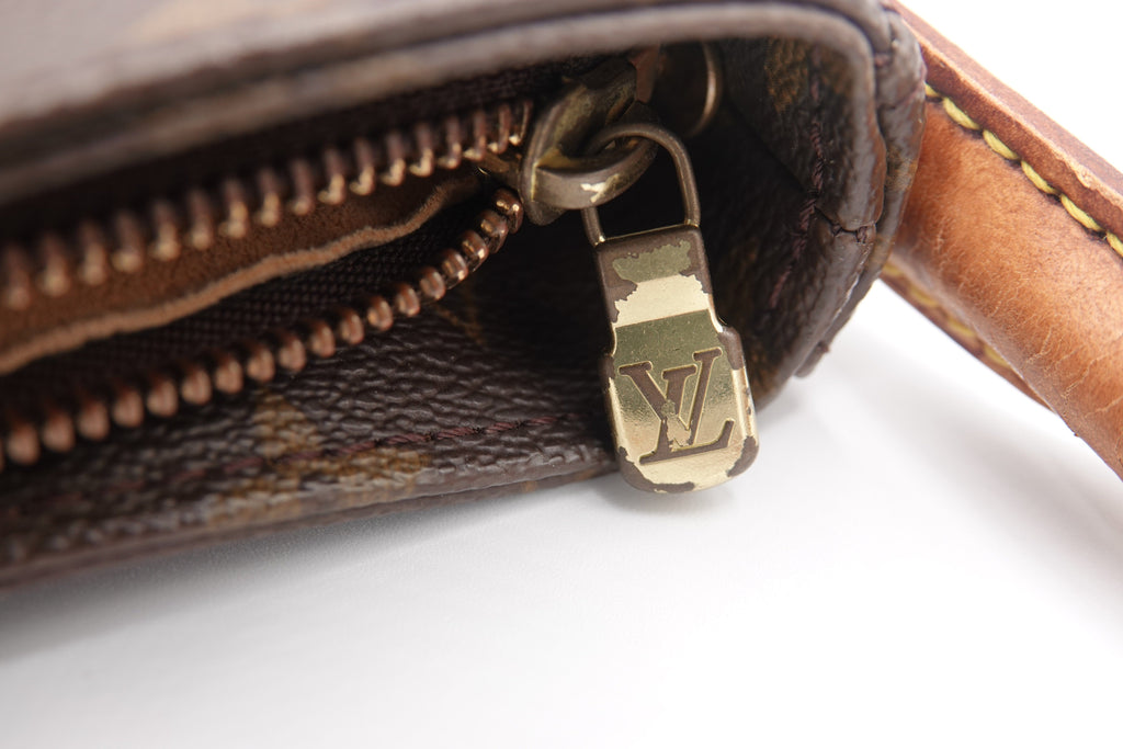 Close-up of a brown leather wallet with a gold zipper pull on a white background