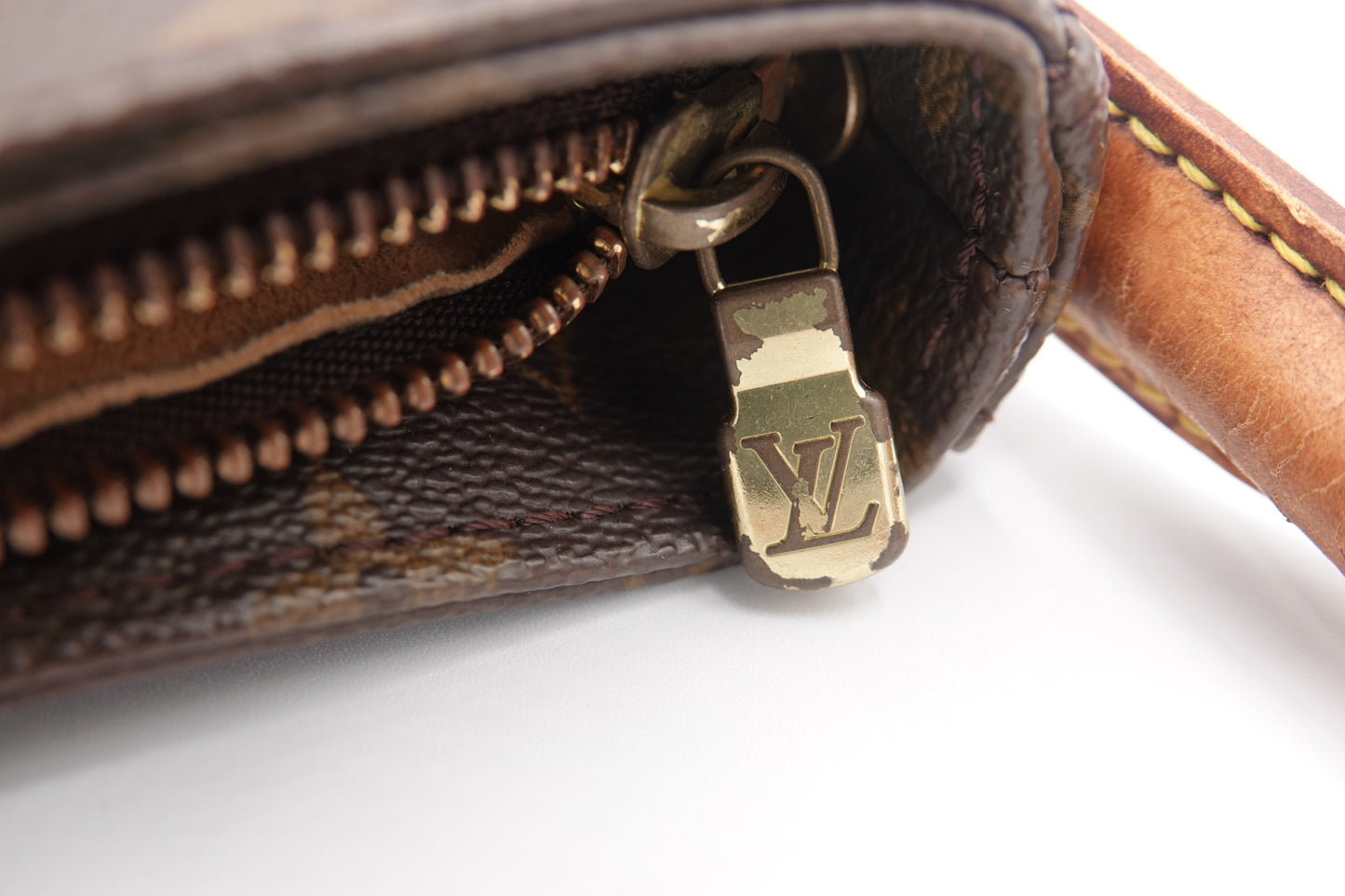 Close-up of a brown leather wallet with a gold zipper pull on a white background