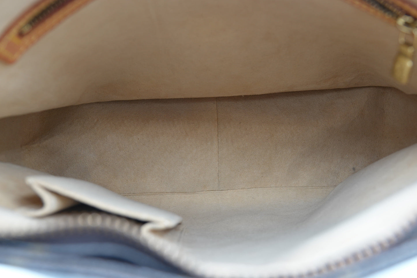 Close-up of a beige leather bag with a zipper