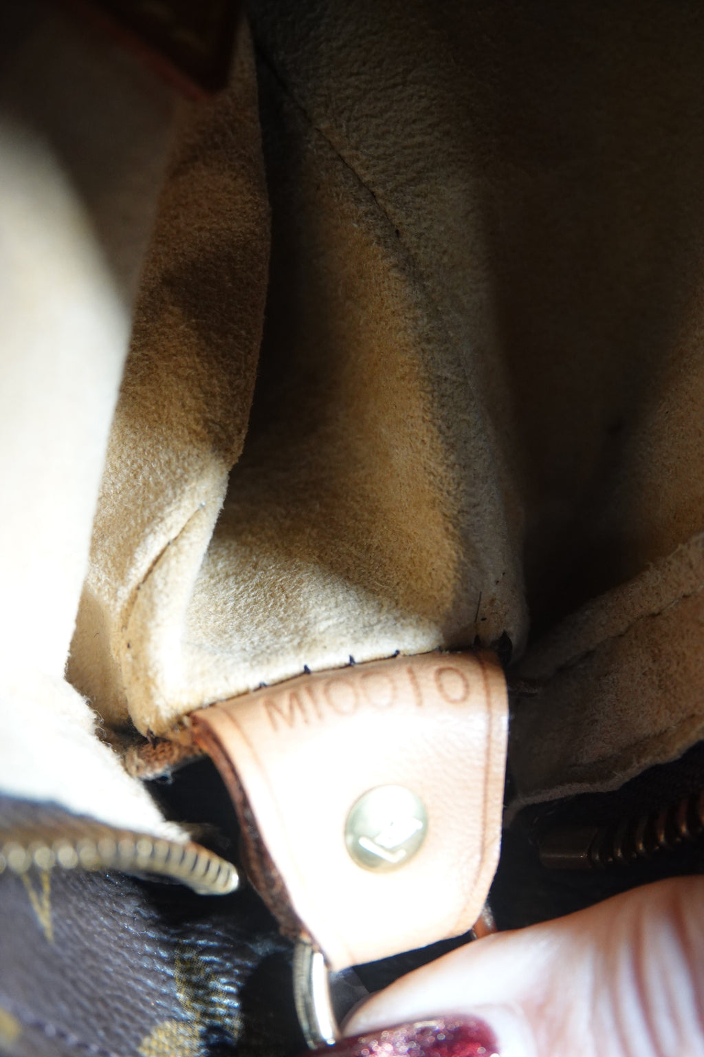Close-up of a brown leather product with a button, possibly a bag or wallet.