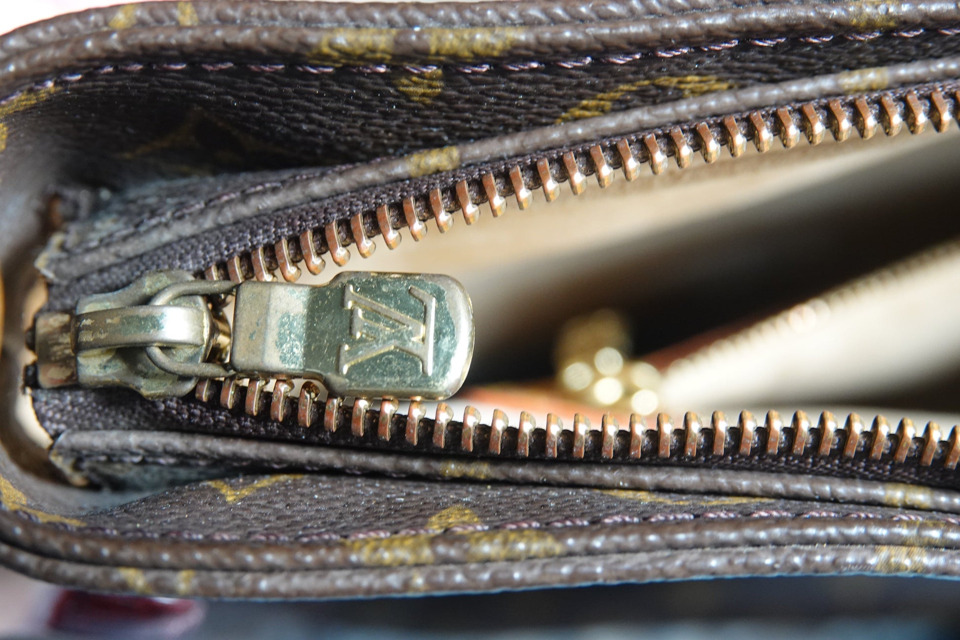 Close-up of a zipper on a Louis Vuitton wallet with a blurred background