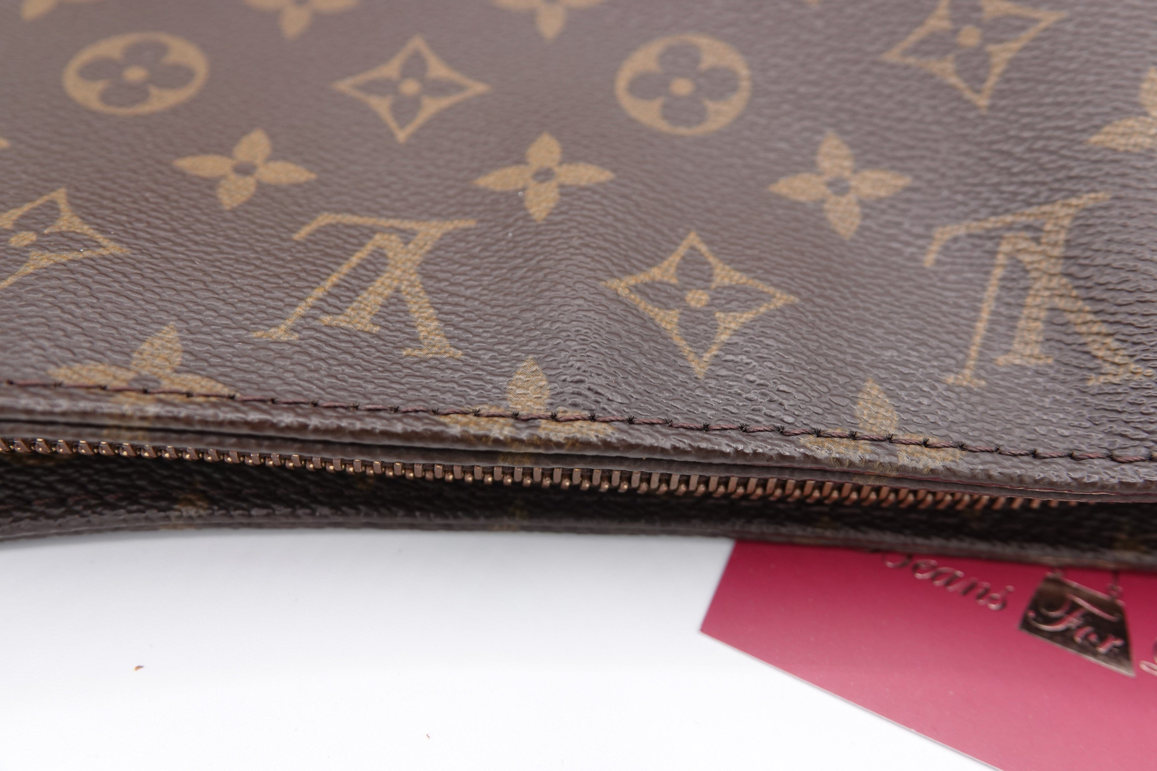 Brown leather wallet with gold monogram pattern on a white background