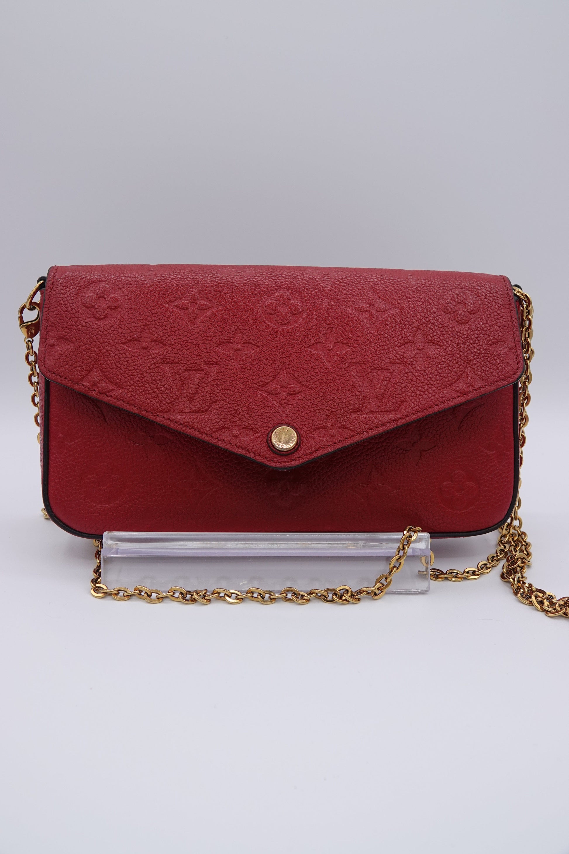 Red handbag with gold chain on a light gray background