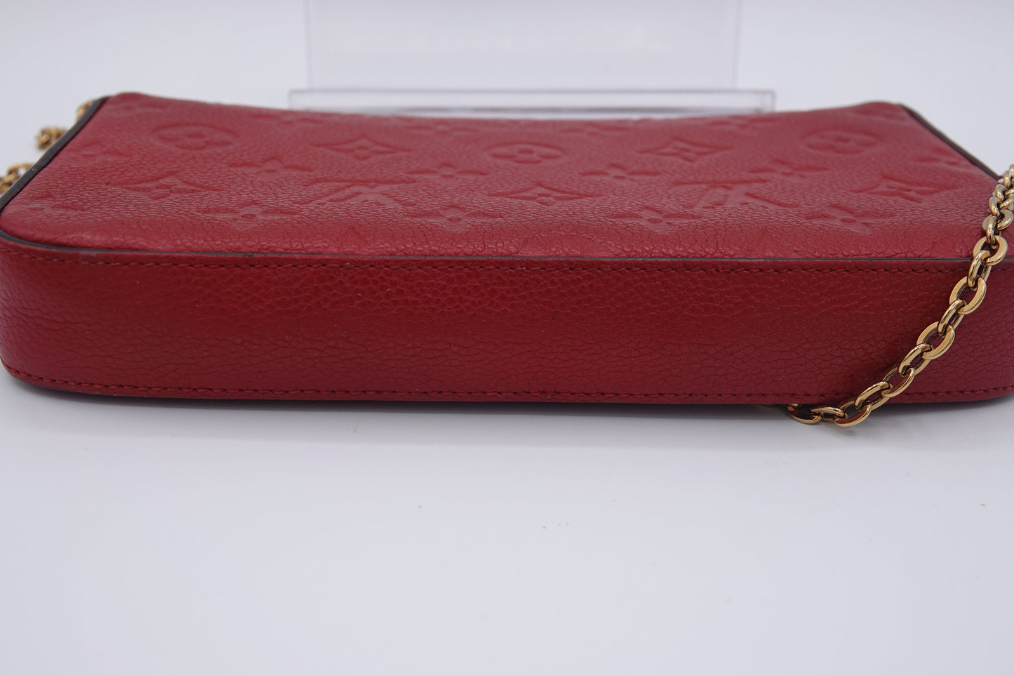 Red leather wallet with gold chain on a white background
