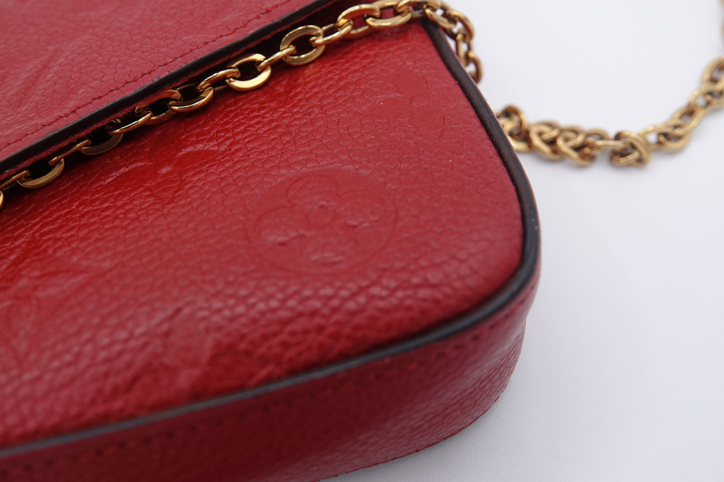 Red handbag with gold chain strap on a white background