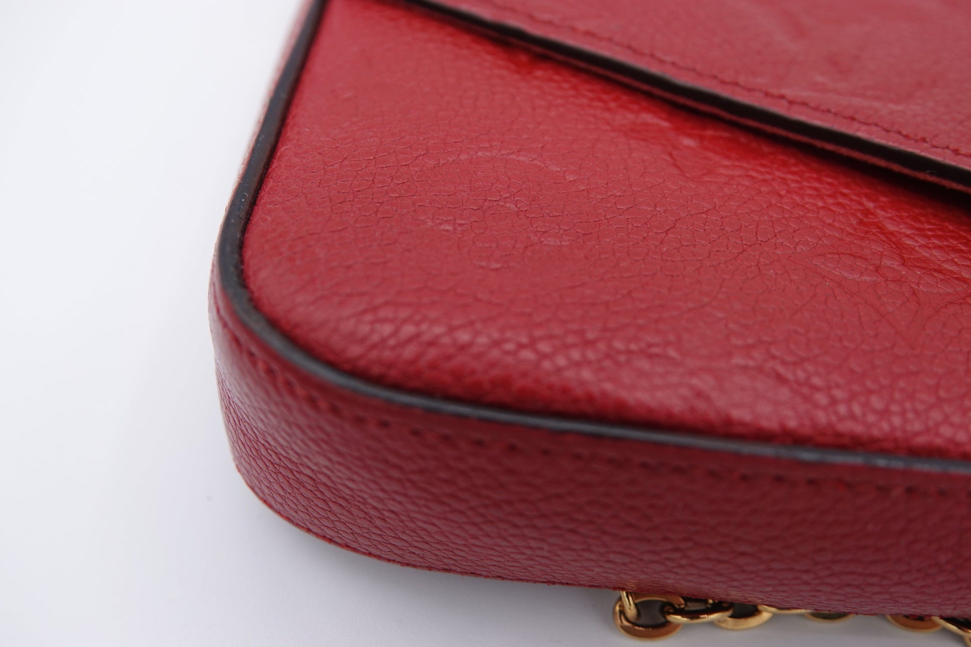 Close-up of a red handbag with a gold chain on a white background