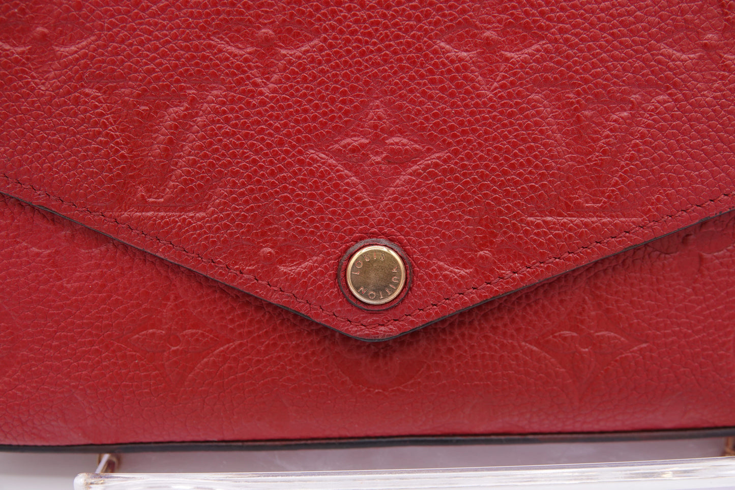 Close-up of a red leather handbag with gold emblem
