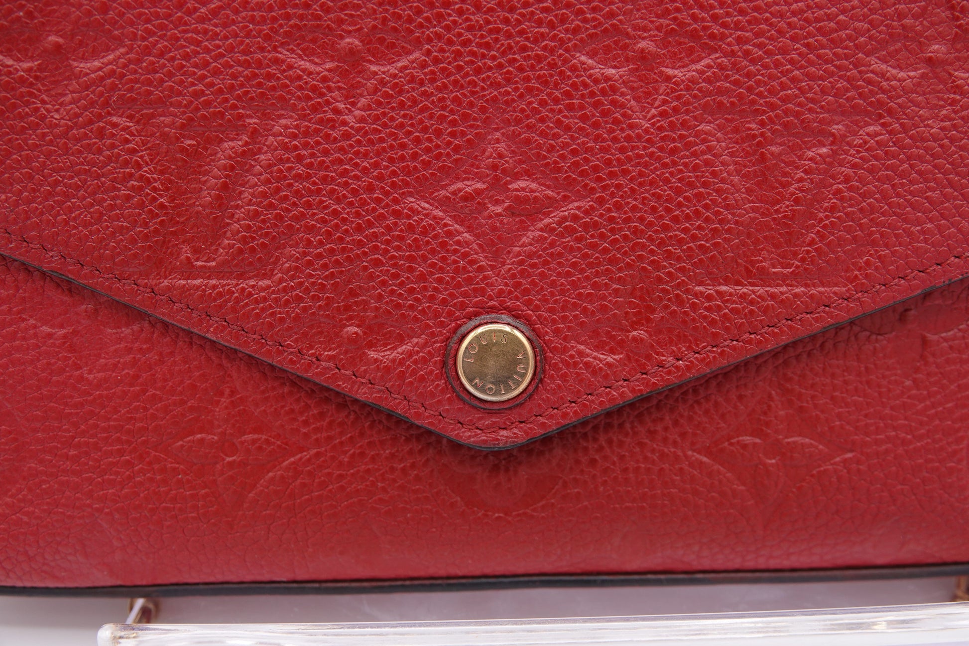 Close-up of a red leather handbag with gold emblem