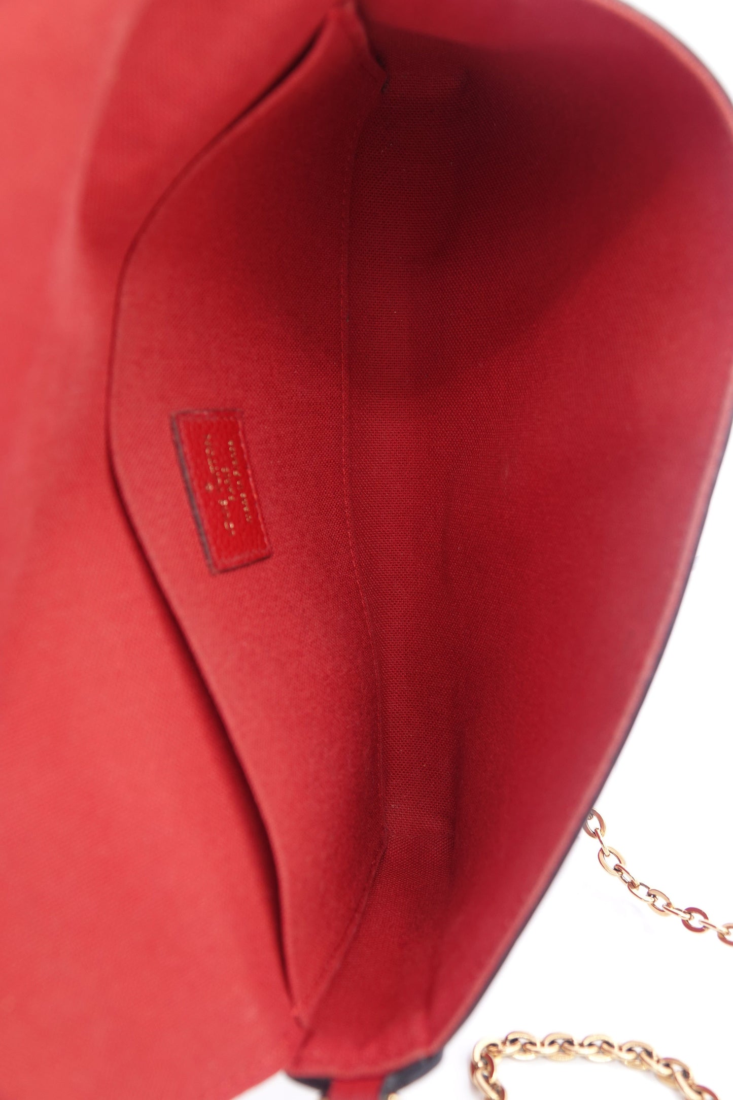 Close-up of a red handbag with a gold chain on a white background